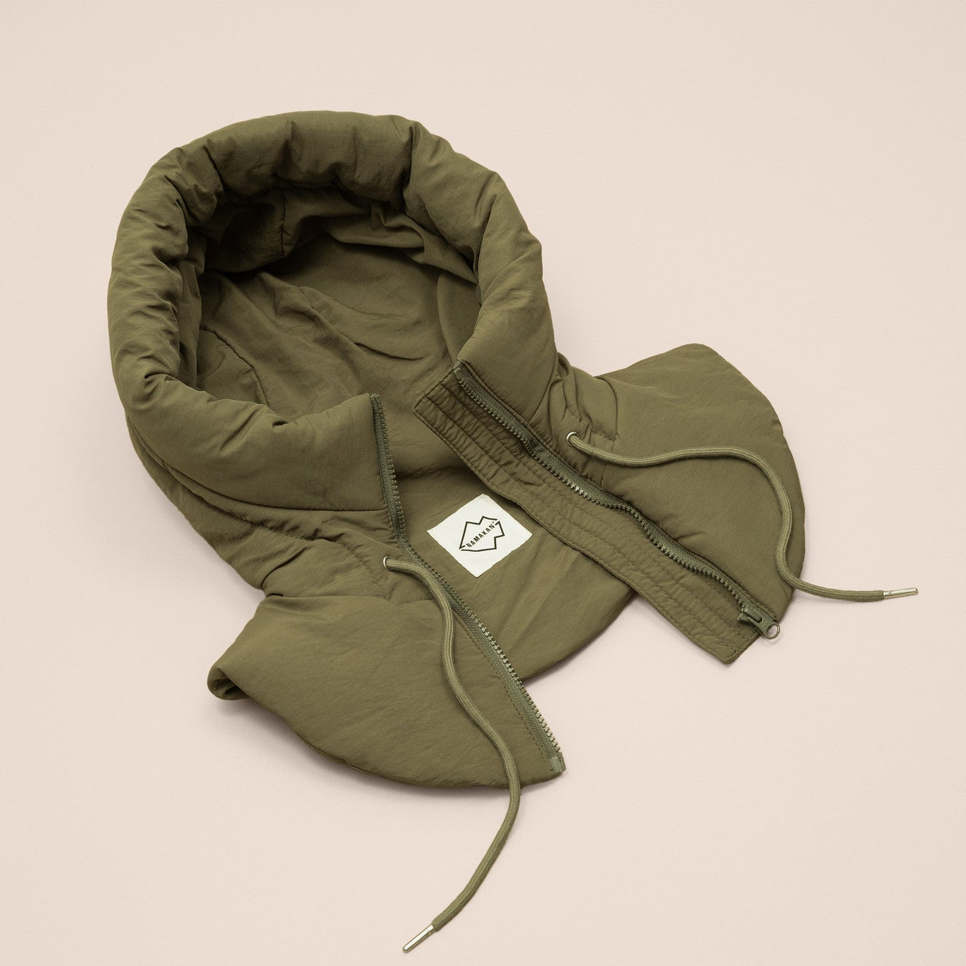 Green puffer hood with a brand label on a beige background