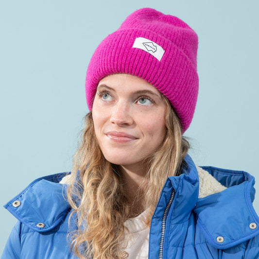 Person wearing a blue jacket and pink beanie against a light blue background
